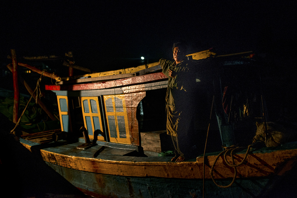 A shrimp fisherman stands on the gunnels of his vessel
